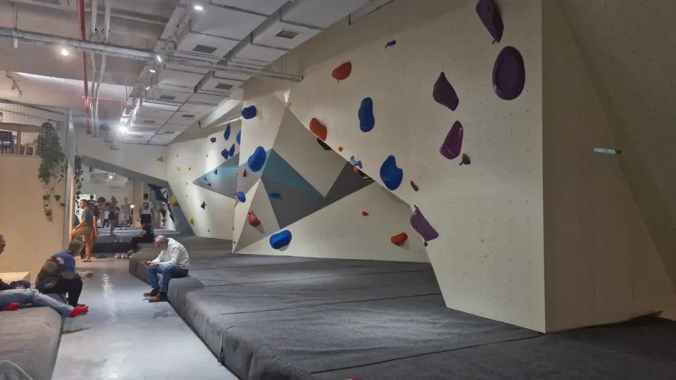 Long angled bouldering wall with grey matting and seating