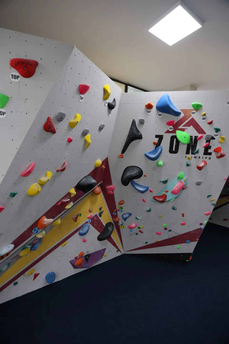 Angled bouldering panels with volumes beneath the Zone logo
