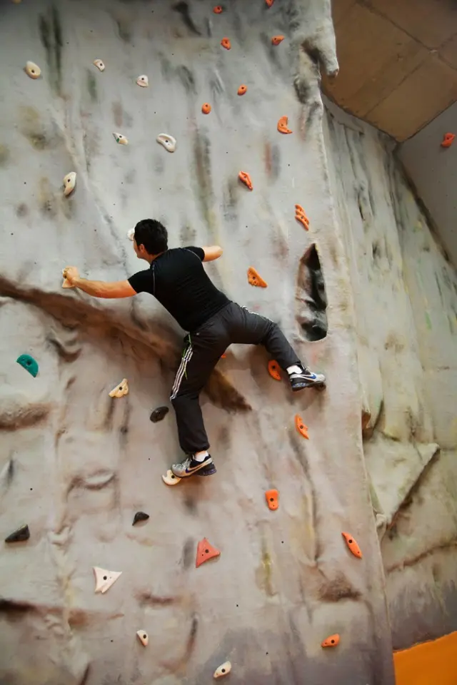 Climber moving up the rock-textured section of the climbing wall