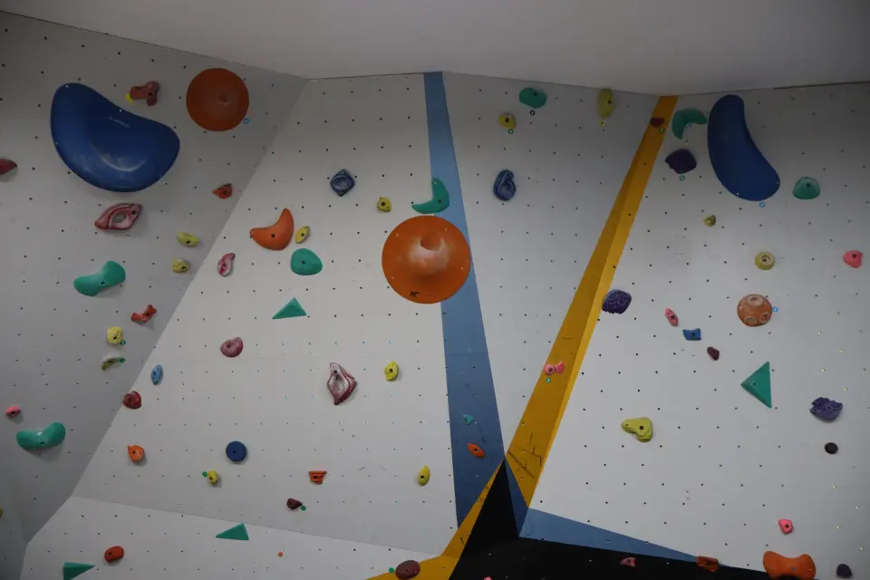 Angled bouldering walls with blue and orange volumes and colourful holds