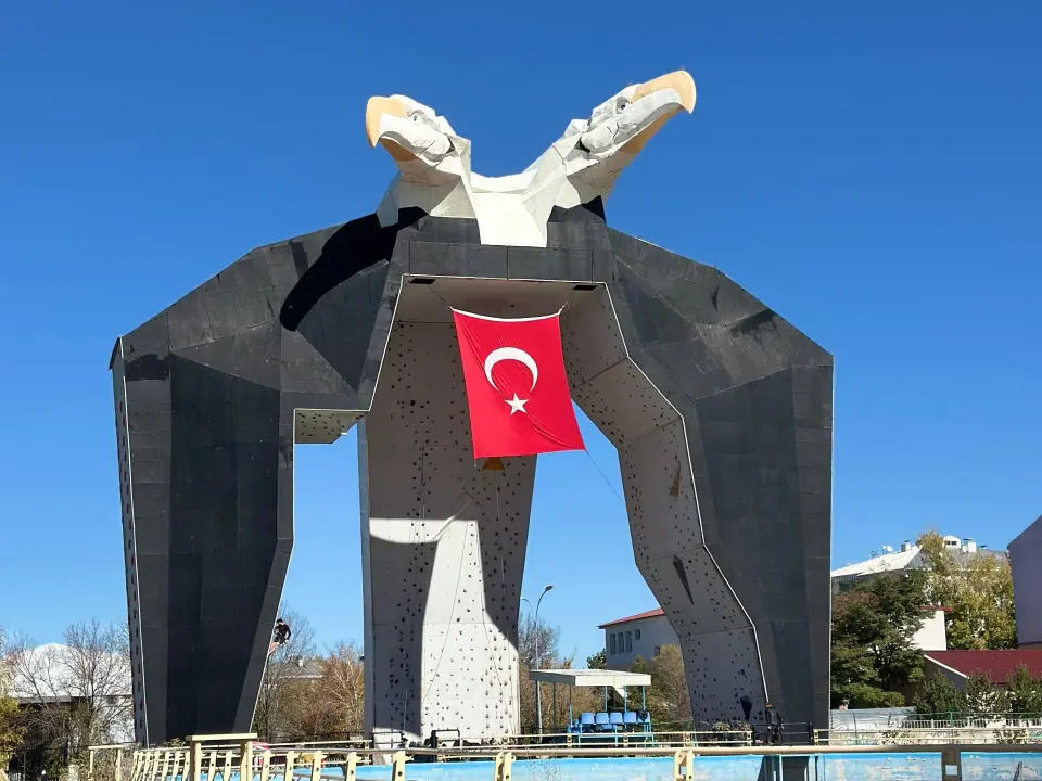 Outdoor climbing tower topped by a double-headed eagle, with a Turkish flag hanging between its arms