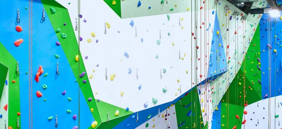 Tall blue, green and white rope walls hung with quickdraws and top ropes