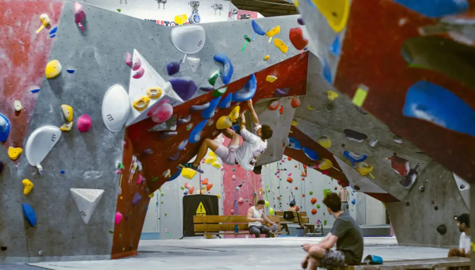 Climber under a steep red and grey bouldering overhang