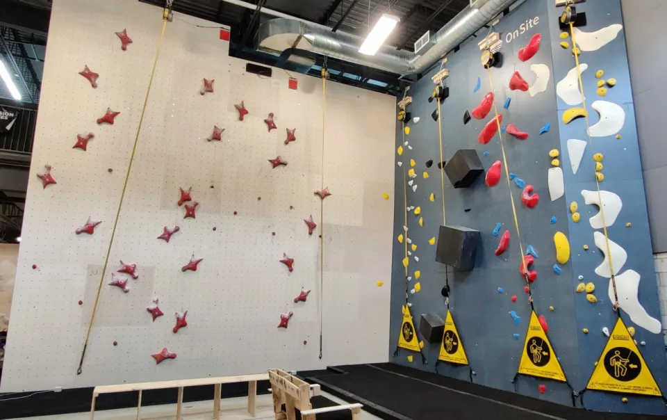Auto-belay lanes on a blue wall beside a taller top-rope wall