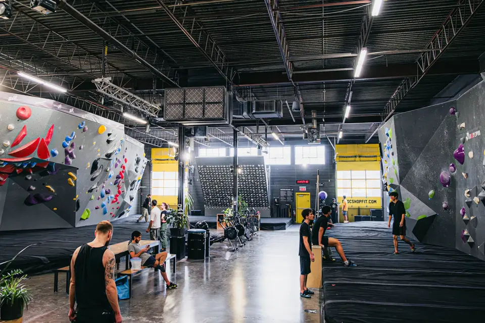 Bouldering hall with padded floors, walls on both sides and a training board at the far end