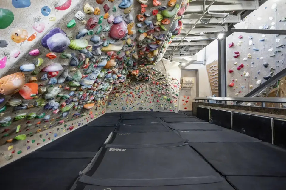 Matted bouldering cave packed with holds on the mezzanine