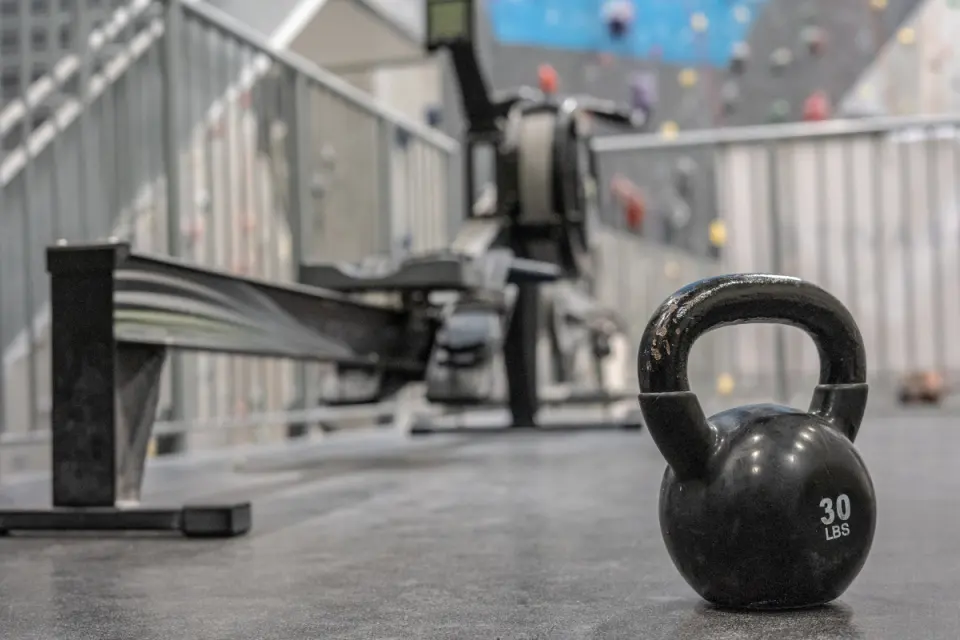 Kettlebell and rowing machine in the training area, with climbing walls behind
