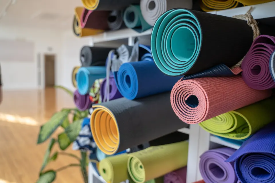 Rolled yoga mats stacked on shelves in the bright yoga studio