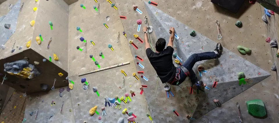 Climber leading a route past a grey triangular volume on a textured wall