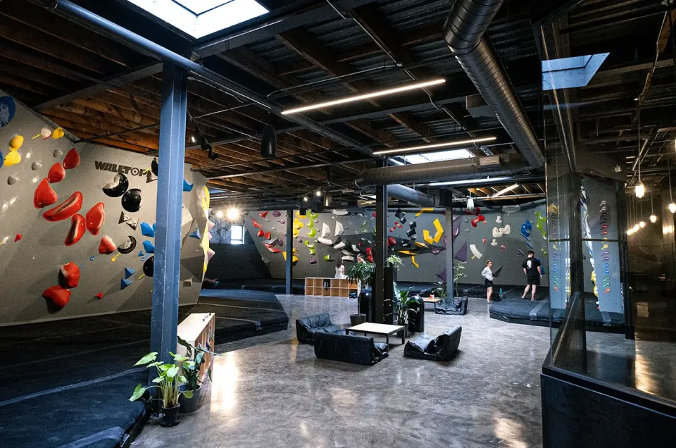 Bouldering hall with grey walls, bright holds and a seating area in the middle