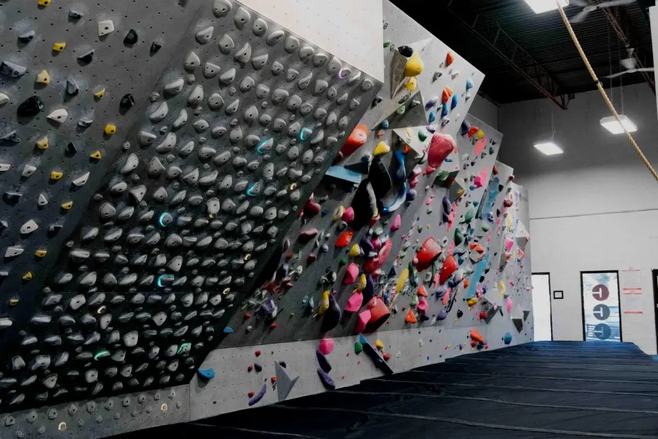 Kilter Board beside the main bouldering wall, with matting below