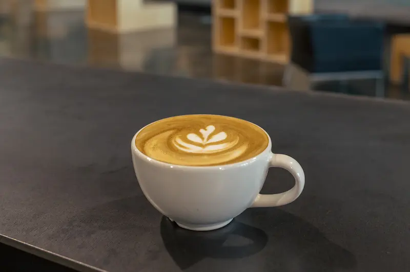 Latte with leaf art on a dark table in the café