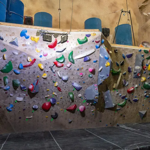 Bouldering wall packed with colourful holds above dark matting