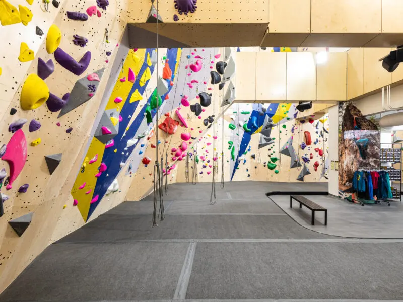 Roped walls with yellow, blue and grey panels and ropes hanging over a grey floor