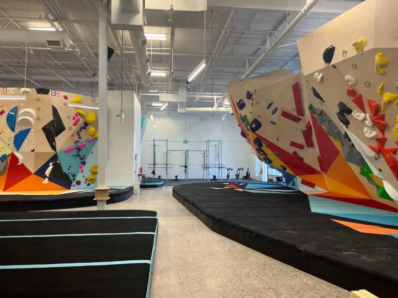 Bouldering hall with padded islands, an overhanging prow and the training area beyond