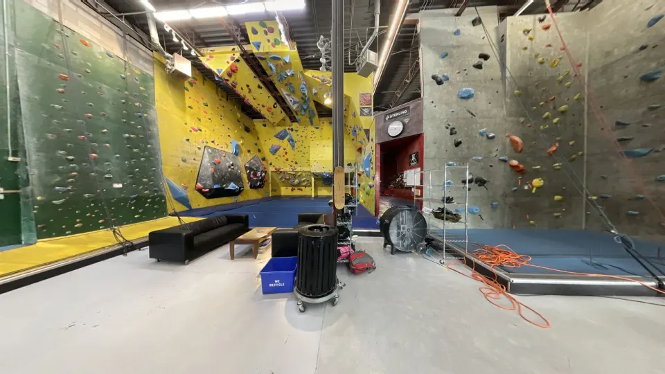 Yellow bouldering room with angled volumes, between tall green and grey roped walls