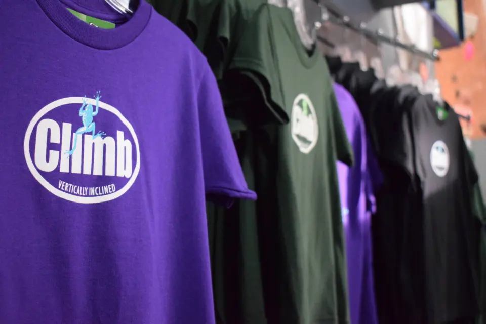 Rack of Vertically Inclined climbing T-shirts in the gym shop