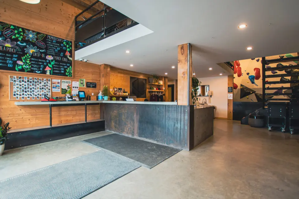 Reception and café counter with a chalkboard price list and wooden walls