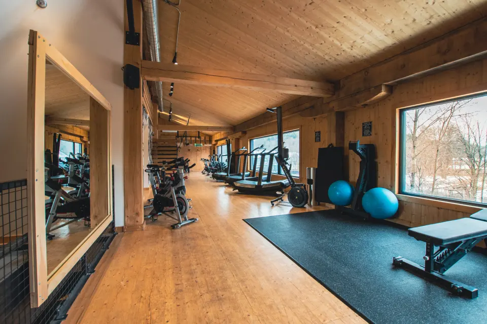 Fitness room with exercise bikes, treadmills, exercise balls and a weight bench under a timber ceiling