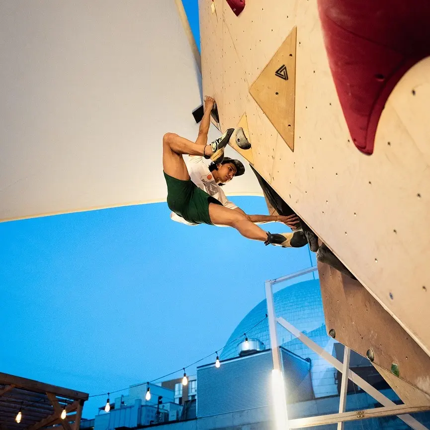 Climber on an overhanging outdoor wall on the rooftop at dusk