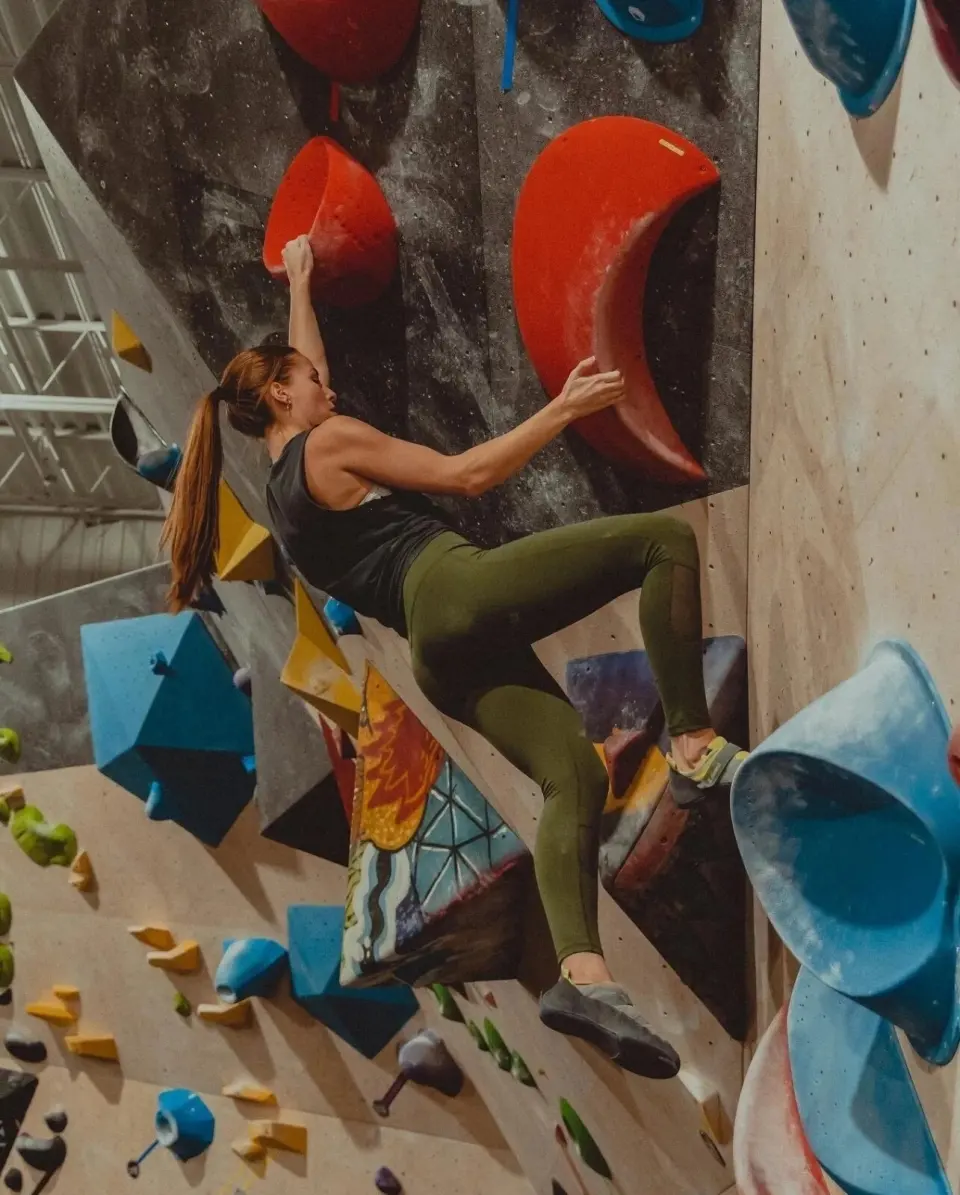 Climber between large red and blue volumes on a bouldering wall
