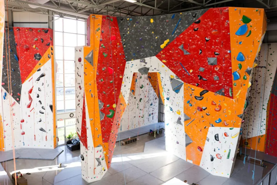 Tall orange, red and grey roped walls in a bright hall with large windows
