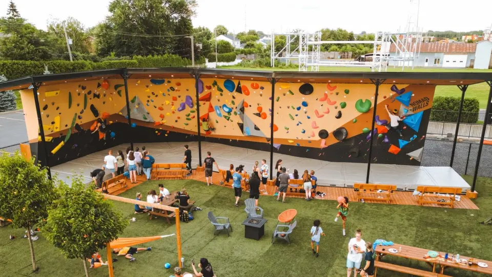 Aerial view of the long outdoor bouldering wall behind the centre, with a lawn and picnic tables