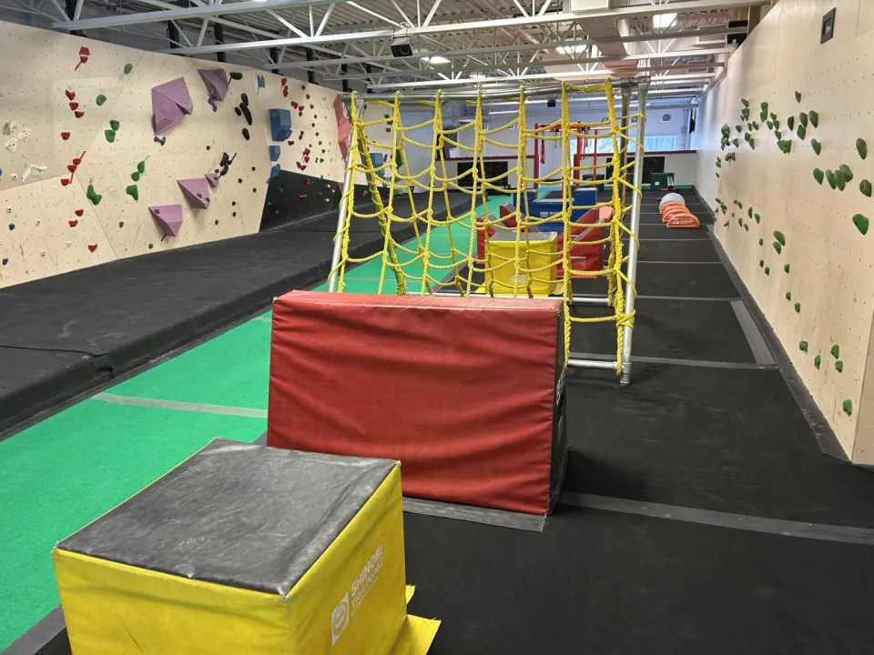 Ninja course with a rope net and padded blocks between bouldering walls