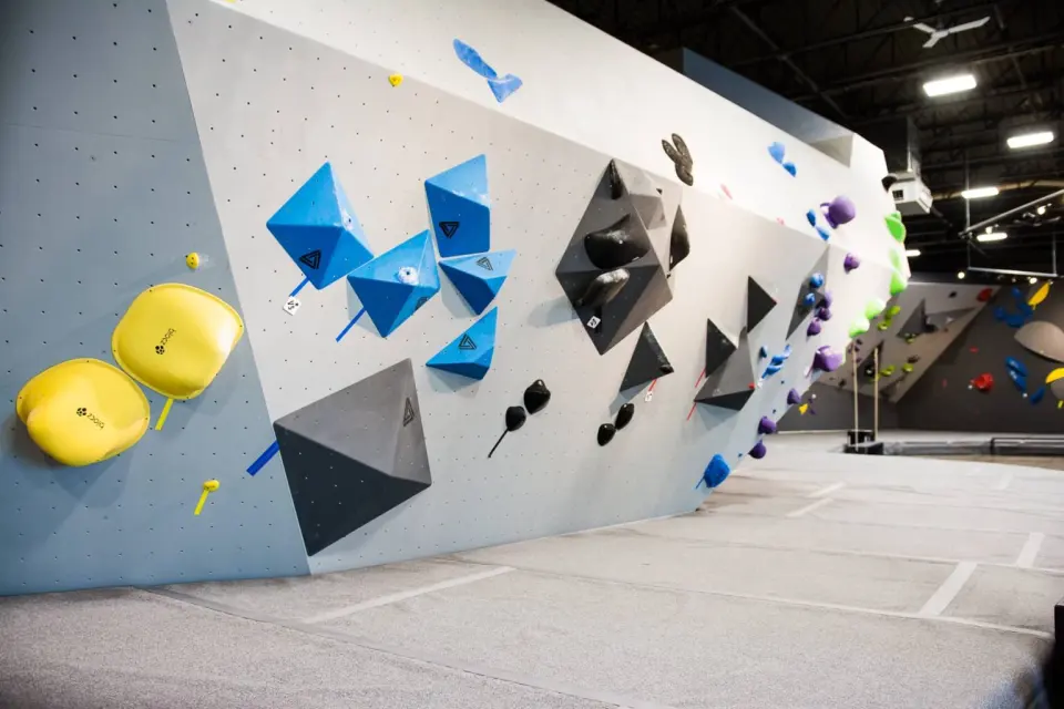 Long pale grey wall set with blue and black volumes and yellow holds
