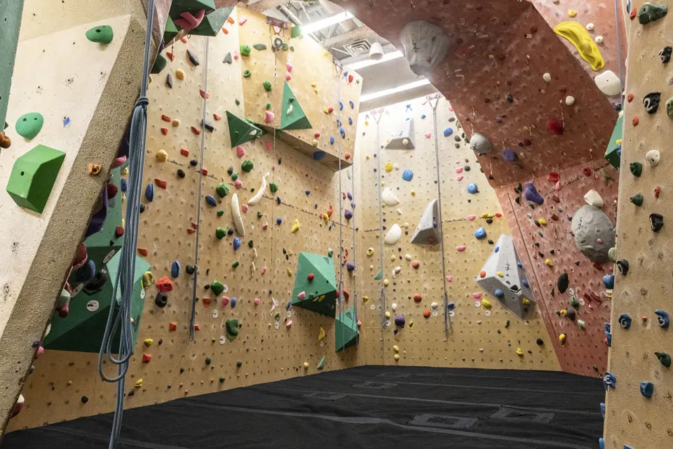 Climbing gym with roped walls, a steep red arch and thick matting on the floor