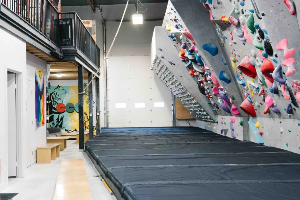 Overhanging grey bouldering wall above deep black mats at Canmore Climbing Gym