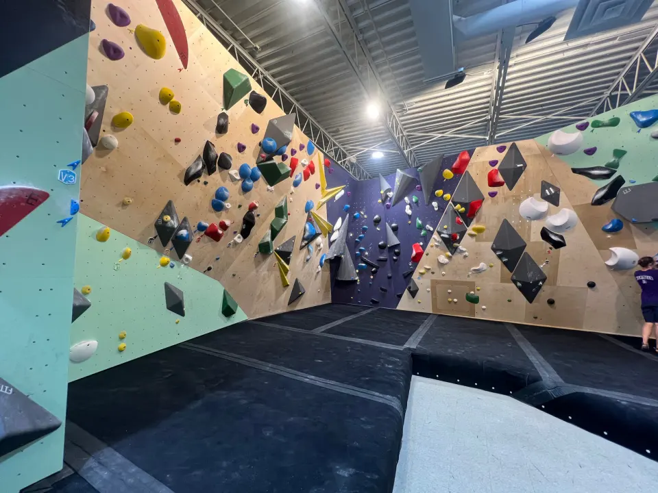 Plywood, mint and purple bouldering walls with grey volumes above black matting