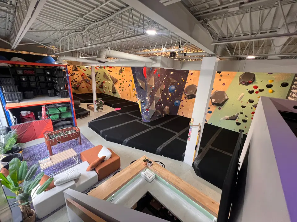 View from the mezzanine over a lounge with sofas and a foosball table to the bouldering walls