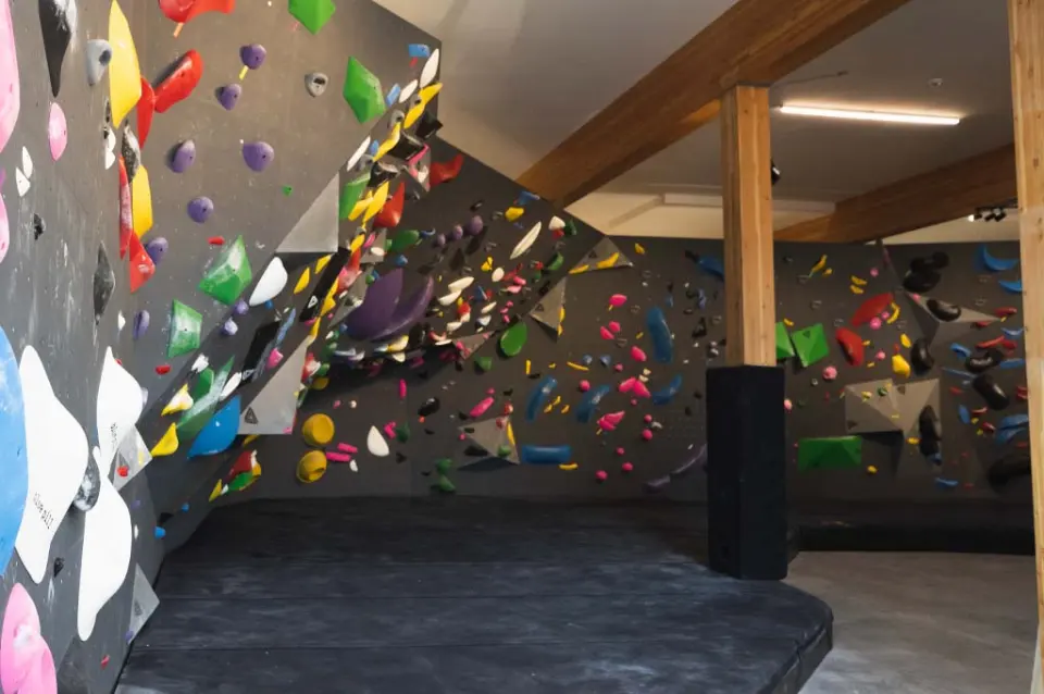 Angled bouldering walls and thick matting beside timber posts