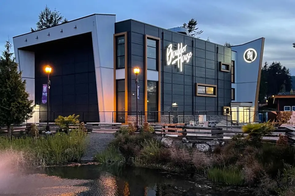 The two-storey gym building lit up at dusk beside a pond