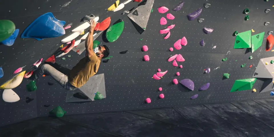Climber hanging from an overhang on the grey bouldering wall