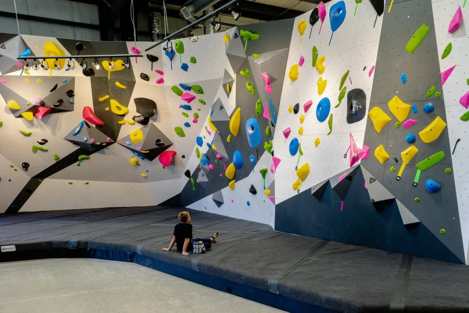 Bouldering walls with overhanging volumes above thick matting