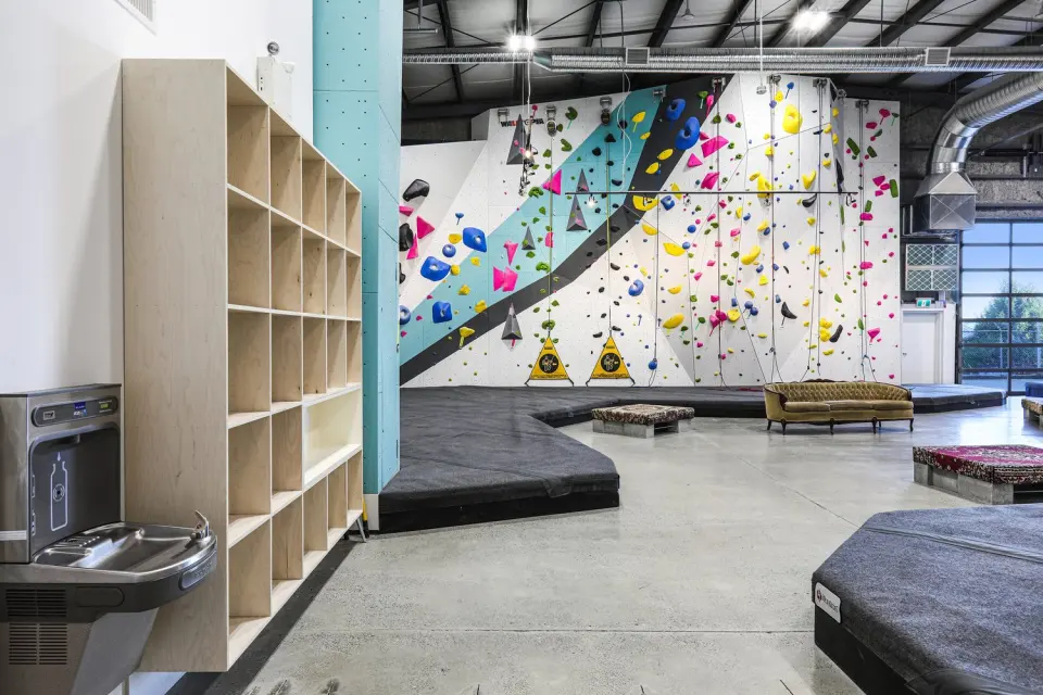 Cubbies and water fountain beside the bouldering floor, with a sofa in the lounge area