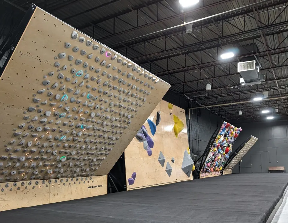 Row of adjustable training boards above thick mats in the Boards and Weights room at Climber's Rock, Burlington