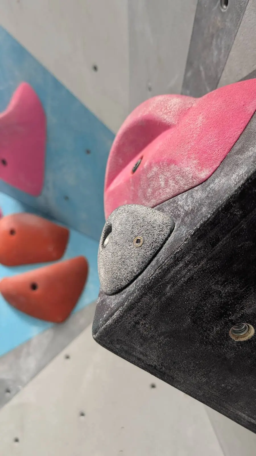 Close-up of chalky pink and black holds on a bouldering volume