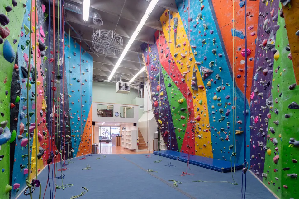 Top-rope corridor lined with tall walls painted in bright stripes, ropes hanging over blue flooring