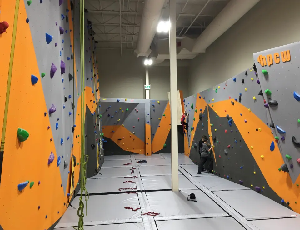 Orange and grey roped walls and bouldering walls above grey matting