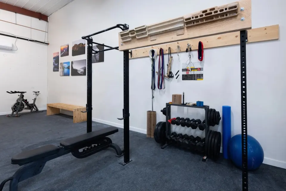 Training area with hangboards, a rack, a bench, dumbbells and a stationary bike