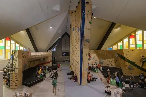 Climbing walls inside the former church, with stained-glass windows and a busy floor
