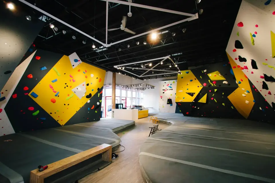 Yellow, black and white bouldering walls above deep grey matting at Gneiss Climbing's original gym on Banks Road, Kelowna