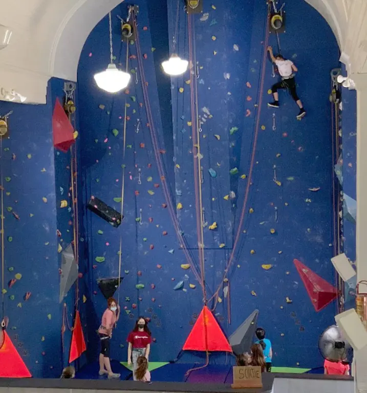 Full-height blue climbing wall with red volumes filling the arched end of the former church
