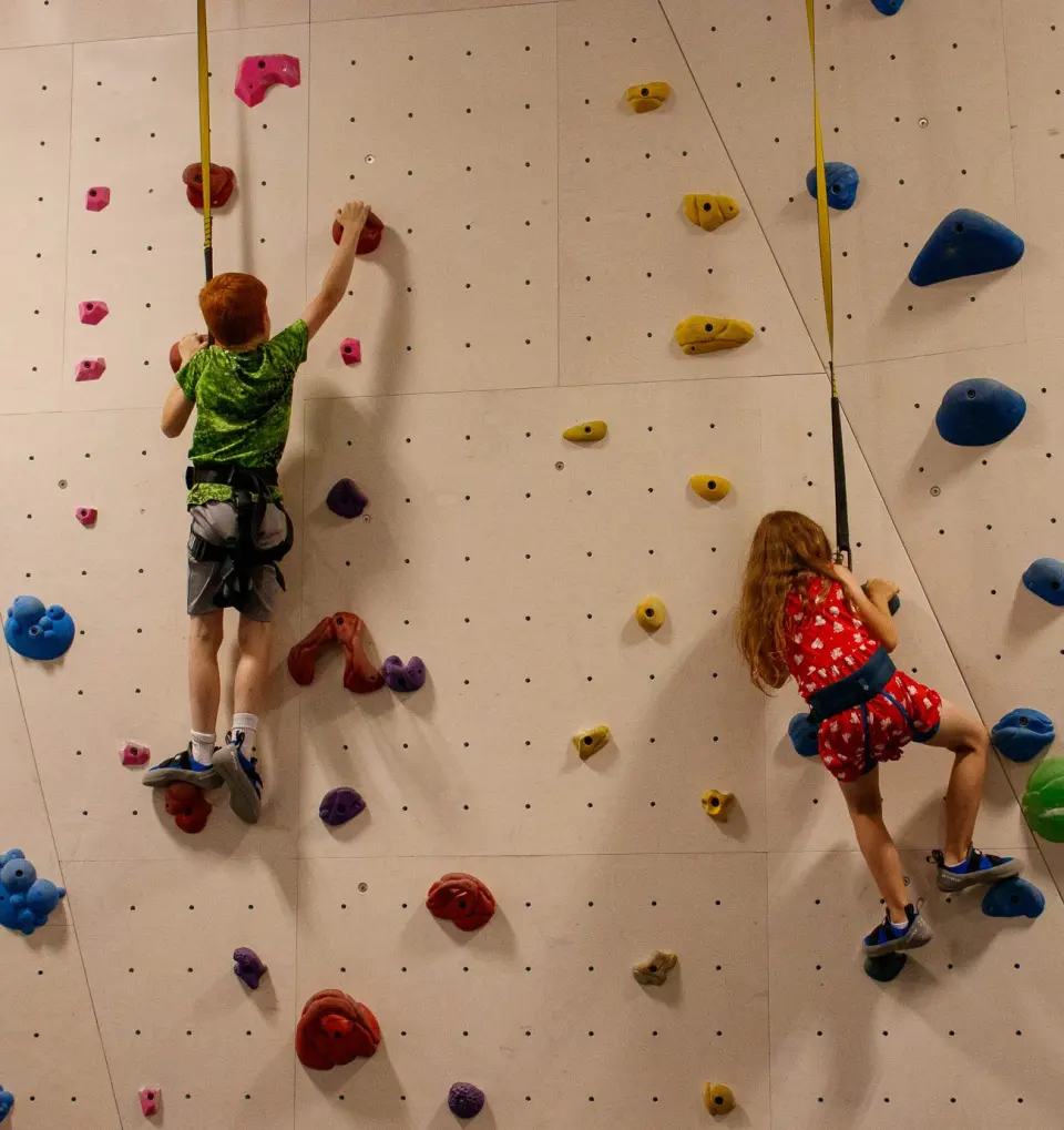 Two young climbers on auto-belays, seen from behind