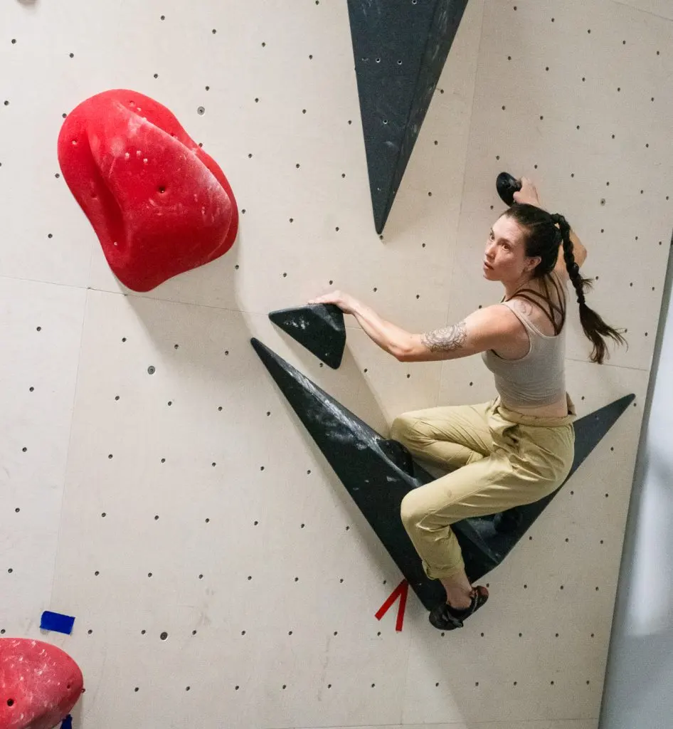 Climber balancing on a black triangular volume