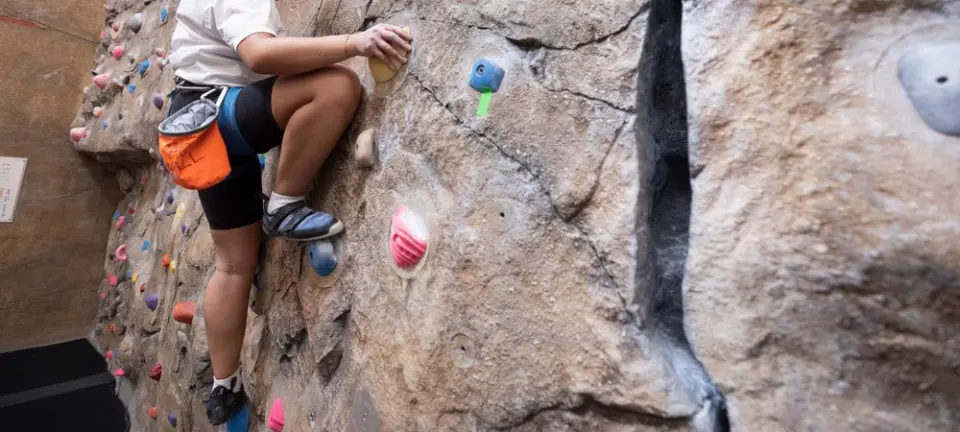 Climber on the rock-textured wall beside a deep crack feature