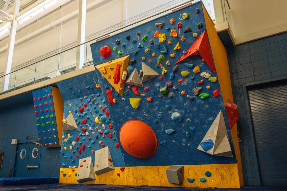Bouldering wall with volumes and a large orange dome above blue matting